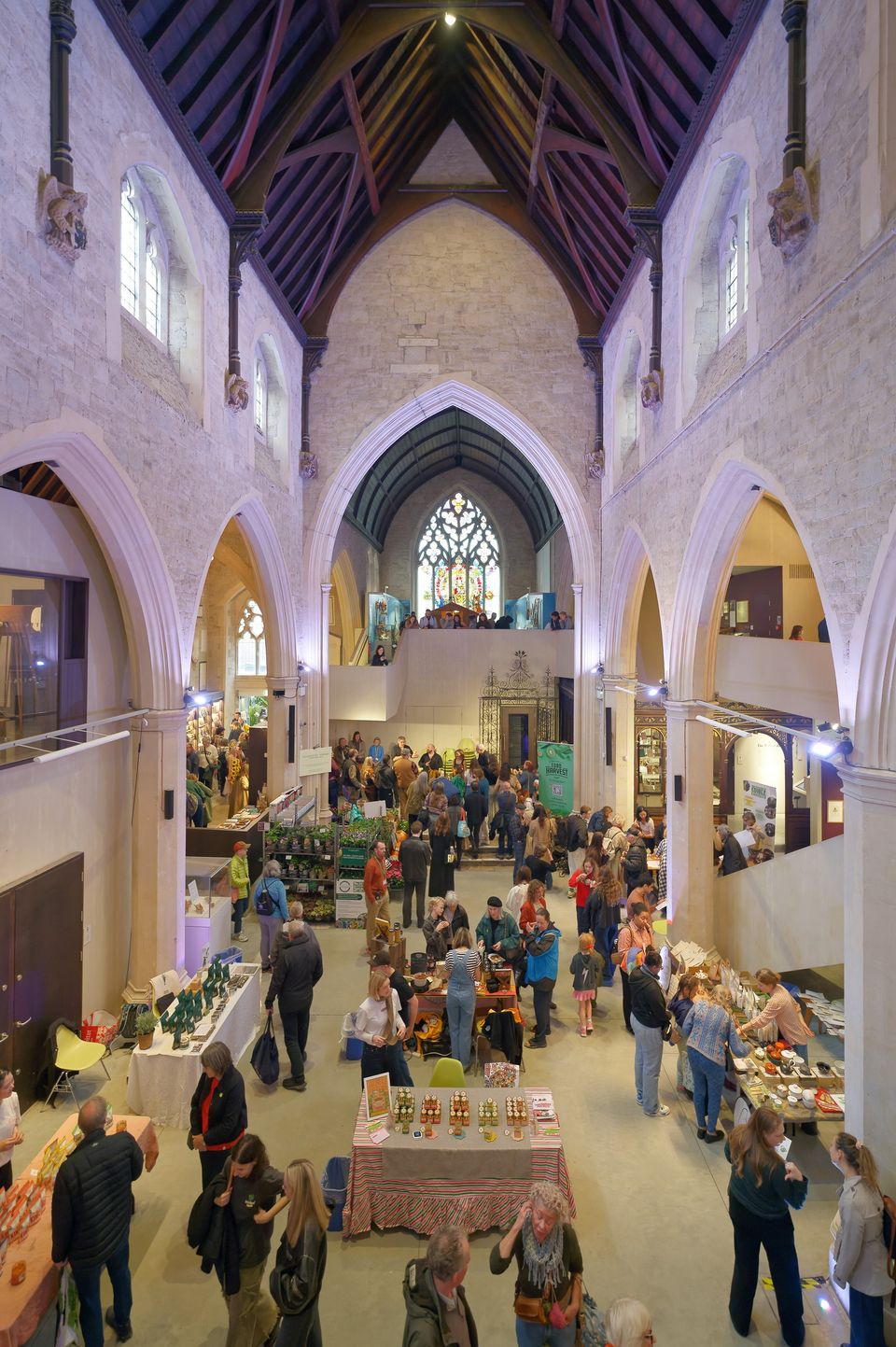 A view across the busy festival hall beneath stained-glass windows